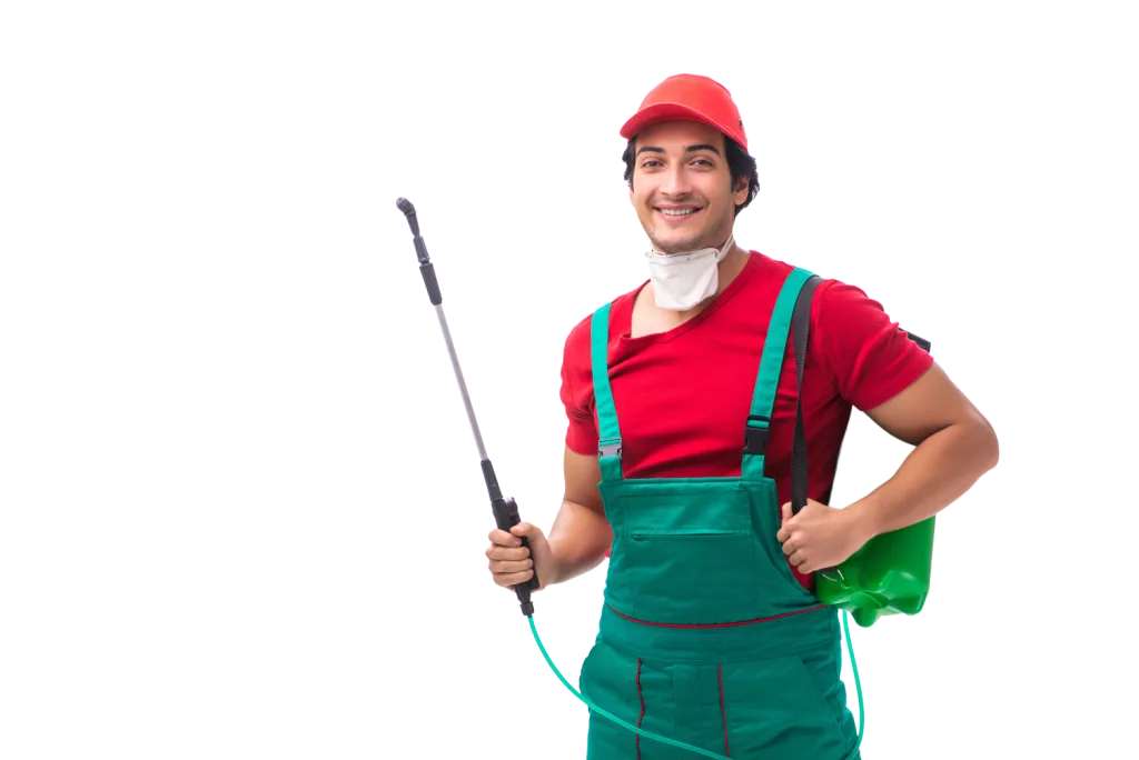 Smiling pest management technician in red cap and green overalls holding a backpack sprayer and treatment wand.